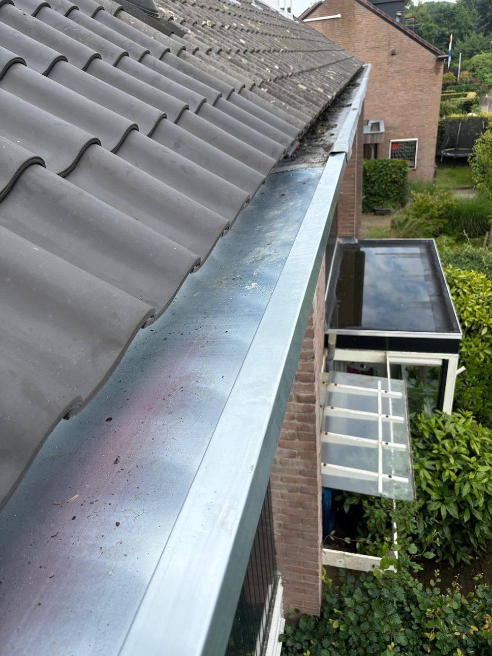 Zinken dakgoot langs een pannendak, close-up