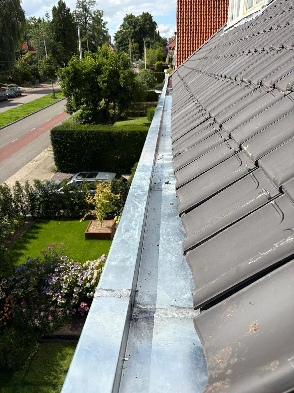 Nieuwe zinken bakgoot met kraal langs de dakrand